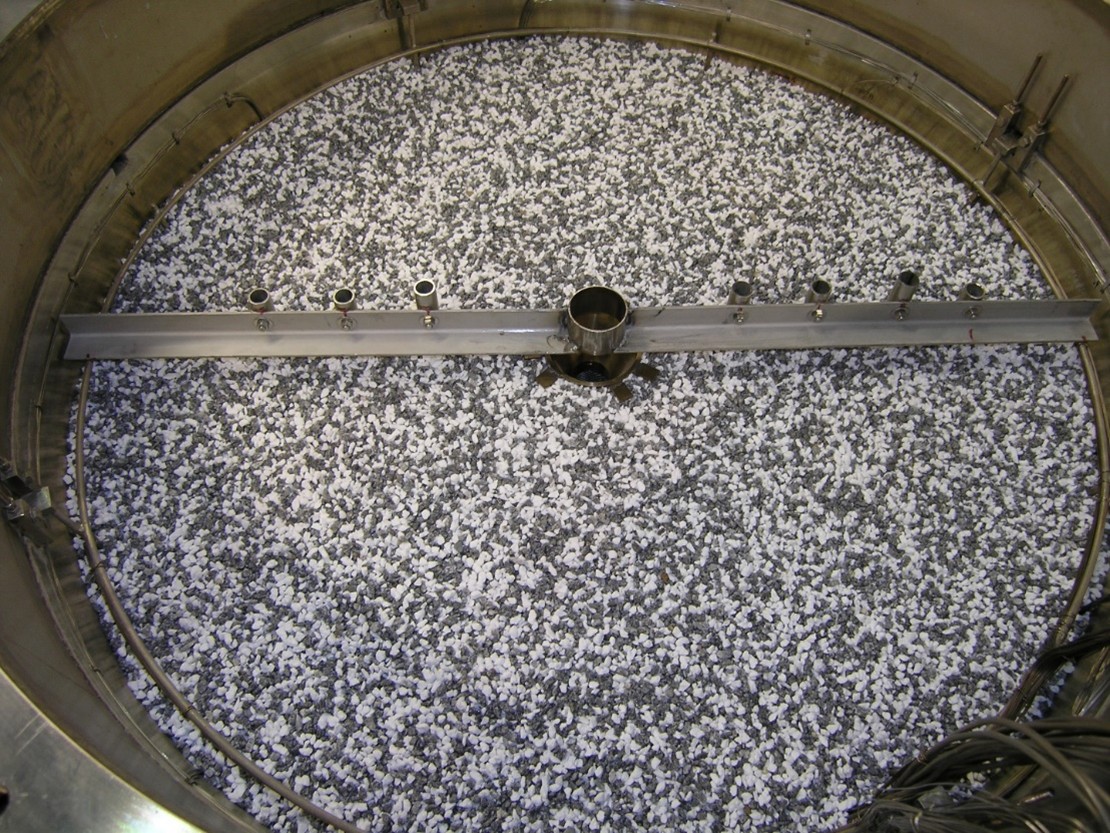 Metallkessel mit grauen und weißen Granulaten für industrielle Anwendungen.
